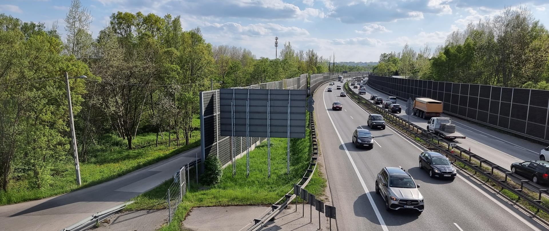 fragment autostrady, dwie jezdnie, panuje duży ruch pojazdów