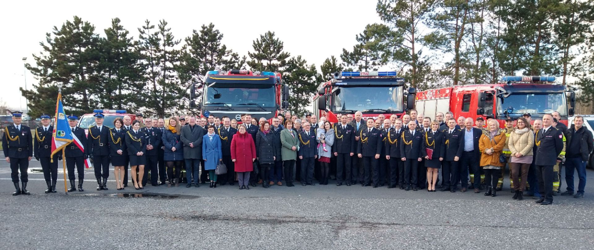 Zdjęcie przedstawia osoby na tle samochodów pożarniczych