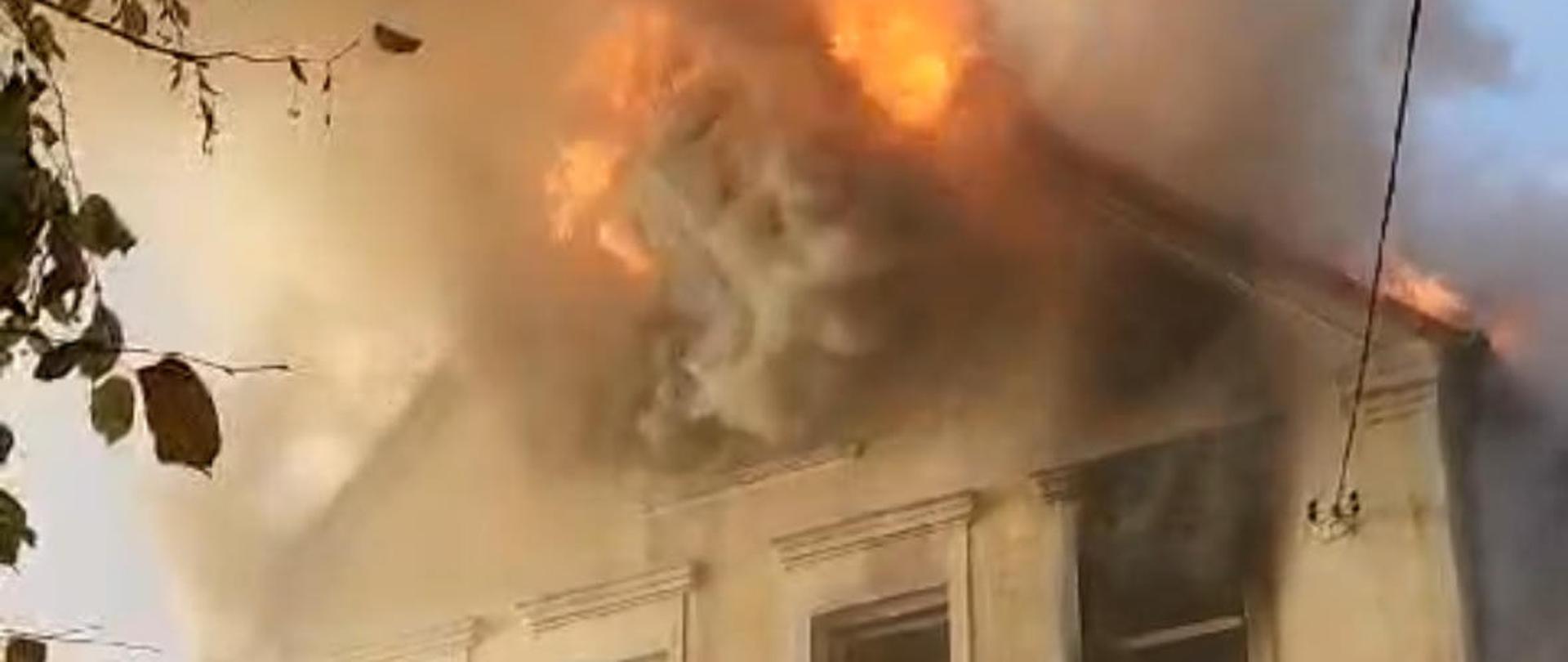 pora dzienna. Kadr przedstawia szczyt budynku objęty ogniem