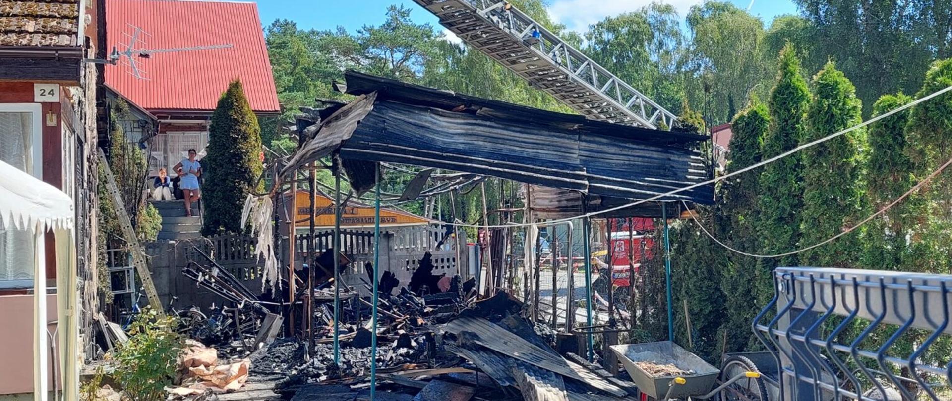 Spalona doszczętnie konstrukcja wiaty w której znajdowała się wypożyczalnia hulajnóg, w tle rozstawiony pojazd straży typu drabina.