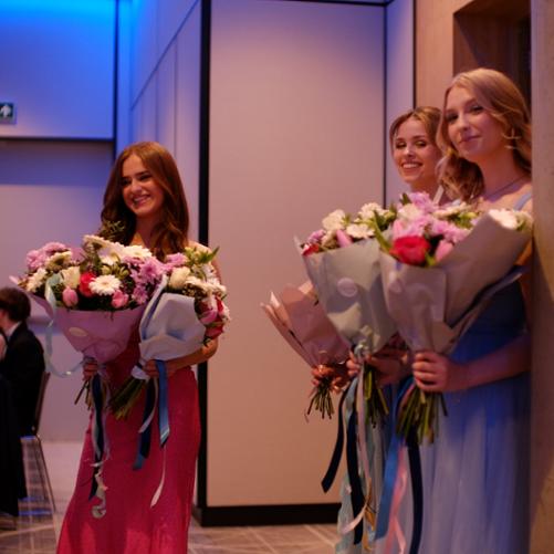 Zdjęcie przedstawia uczennice z kwiatami