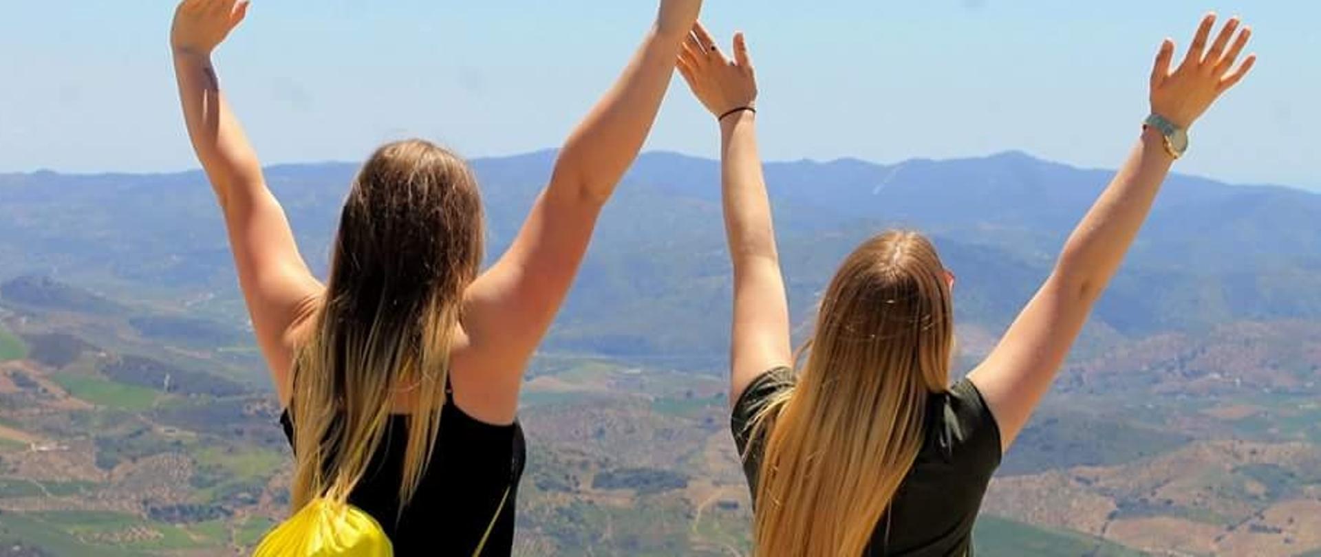 Dwie dziewczyny stojące tyłem na tle górskiego krajobrazu