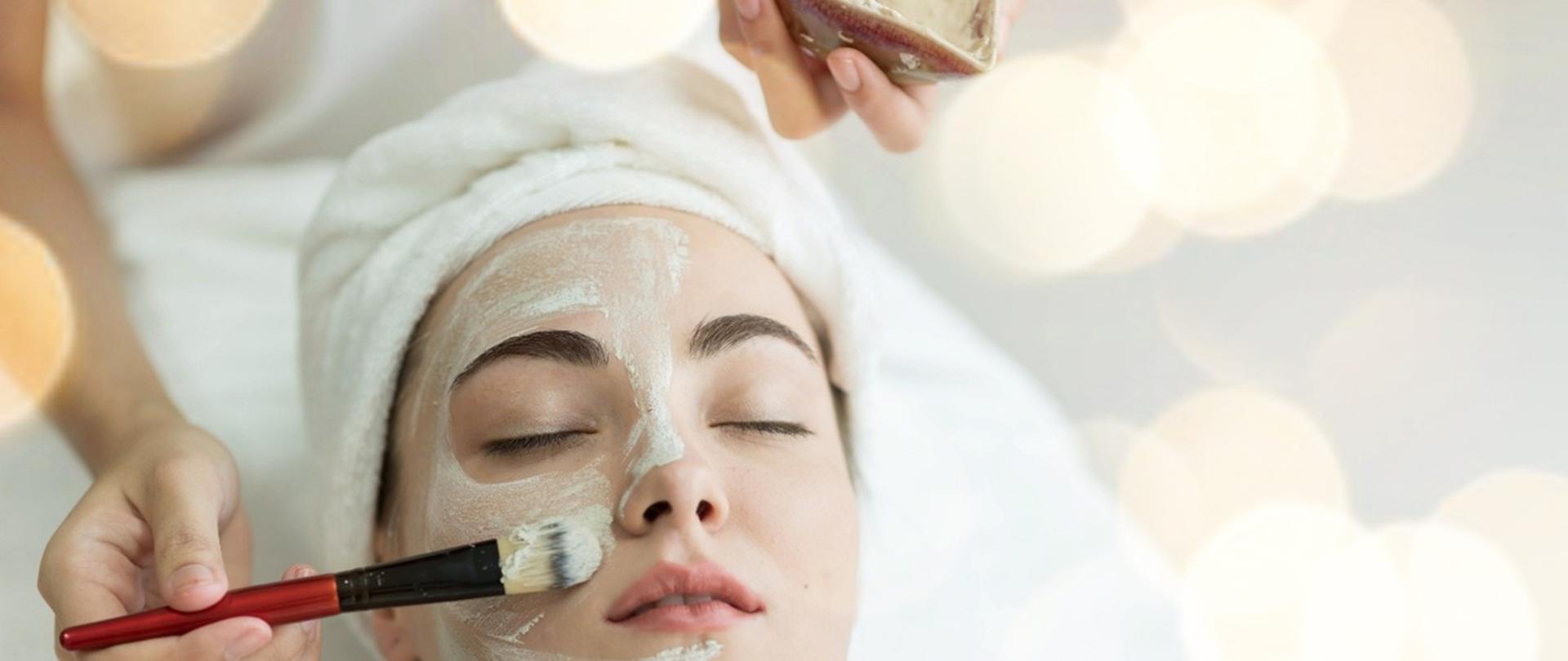 Grafika przedstawiająca twarz kobiety leżącej na łóżku w salonie kosmetycznym, której pędzlem nakładana jest maseczka pielęgnacyjna.