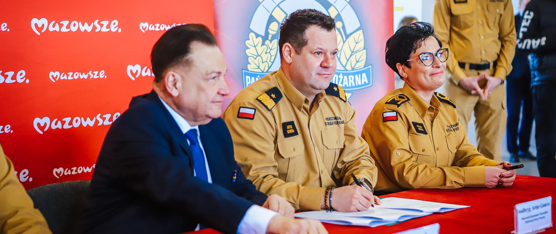 Podpisanie porozumienia przez przedstawicieli samorządu i Państwowej Straży Pożarnej przy stole konferencyjnym.