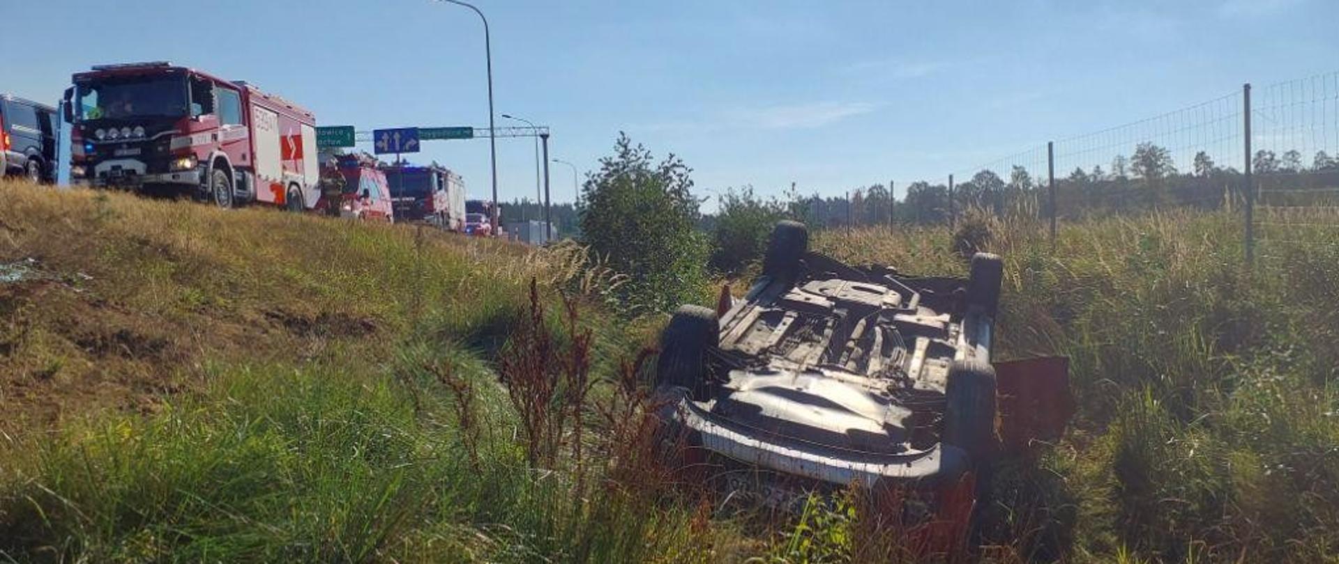 Auto w rowie na dachu, w oddali wozy strażackie