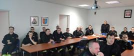 Sala konferencyjna - zebrani strażacy podczas szkolenia. Przemawia Komendant Powiatowy.