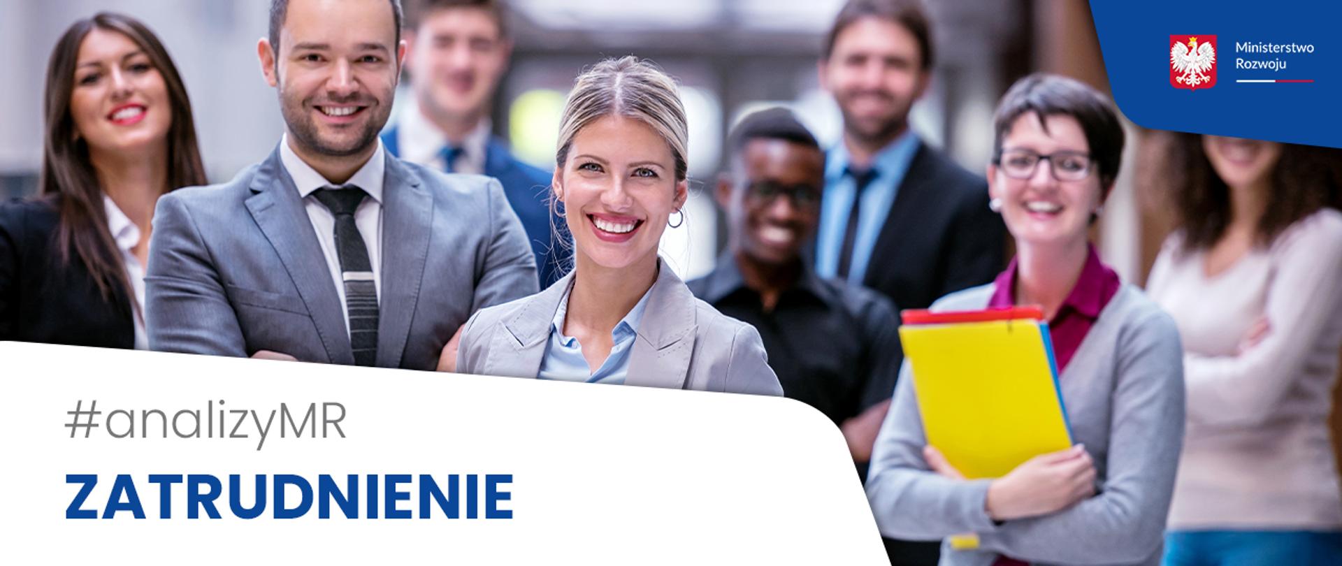 Na zdjęciu grupa ludzi różnej płci. Stoją w luźnej grupie, zwróceni do obiektywu, uśmiechają się. Ubrani w stylu oficjalnym, w garnitury, marynarki, koszule z kołnierzykiem.