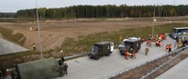 Pozorowany wypadek autokaru i samochodów osobowych. Wokół pojazdy pogotowia i straży pożarnej. Strażacy i ratownicy medyczni ćwiczą udzielanie pomocy poszkodowanym. Żołnierze WOT ustawili obok miejsca zdarzenia namiot do udzielania pierwszej pomocy.