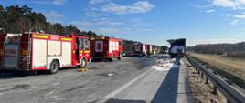 Na zdjęciu widoczne pojazdy pożarnicze oraz zniszczone samochody ciężarowe po zdarzeniu na autostradzie A2.