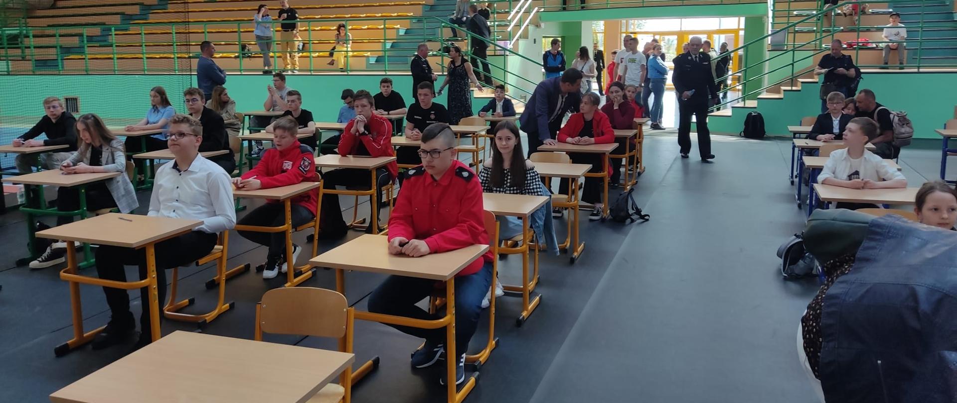 Dzieci siedzą w ławkach