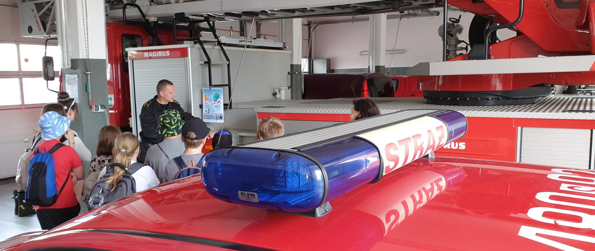 asp. Michał Dyl opowiada przybyłym gościom o działalności straży pożarnej na garażu budynku KM PSP w Jaworznie.