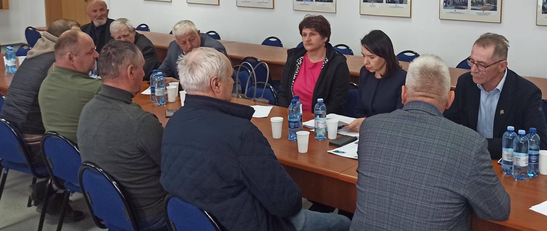 Grupa osób siedząca przy stole w pomieszczeniu.