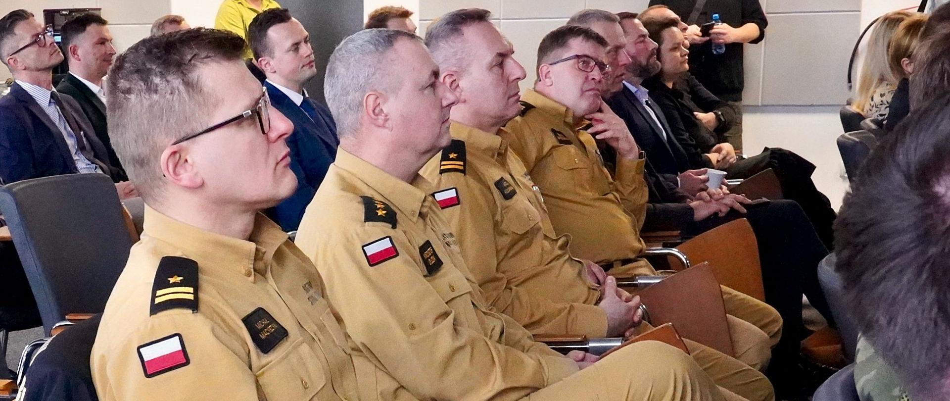 W spotkaniu uczestniczą zaproszeni mundurowi oraz samorządowcy, przebywają na sali.