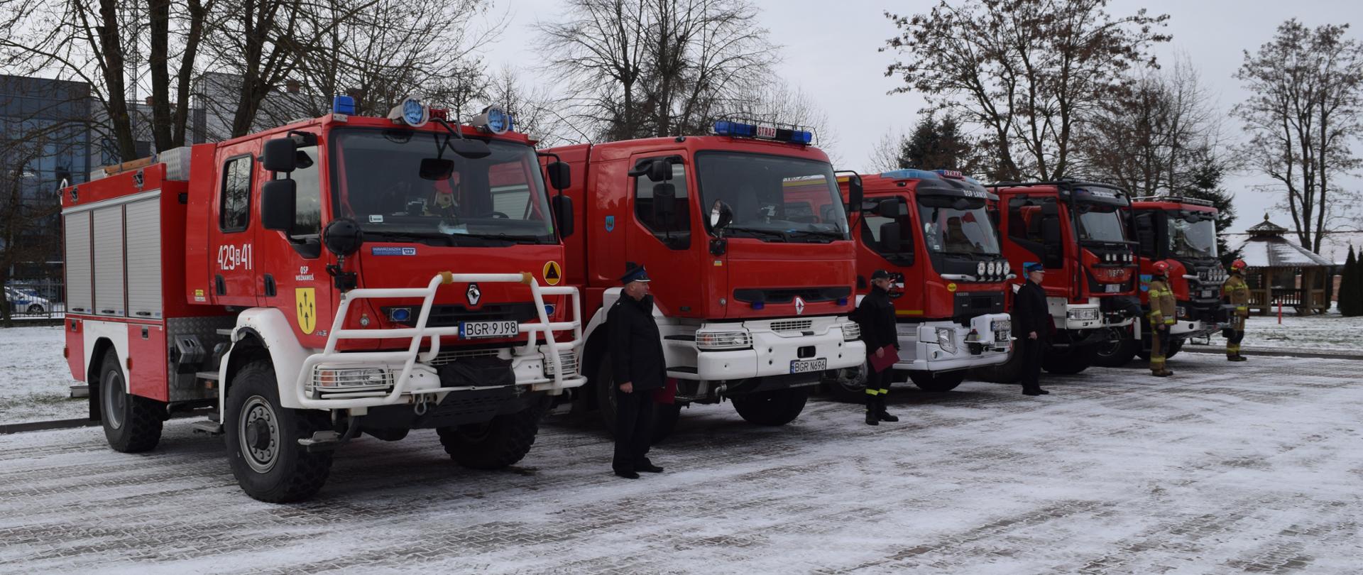 Pojazdy strażackie stoją na placu.
