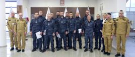 Grupowe zdjęcie uczestników szkolenia (12 osób) w towarzystwie Zastępcy Komendanta Centralnej Szkoły PSP, kobiety oraz trzech strażaków CS PSP