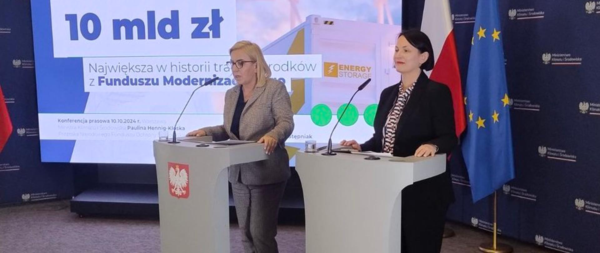Zdjęcie z konferencji przedstawiające 2 stojące kobiety przy pulpitach mównic, od prawej: prezes zarządu NFOŚiGW Dorota Zawadzka-Stępniak, minister klimatu i środowiska Paulina Hennig-Kloska