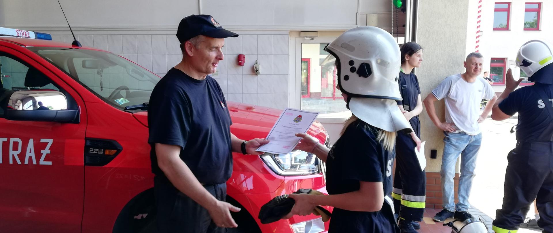 Zastępca komendanta powiatowego PSP w Człuchowie wręcza druhnie świadectwo ukończenia kursu .