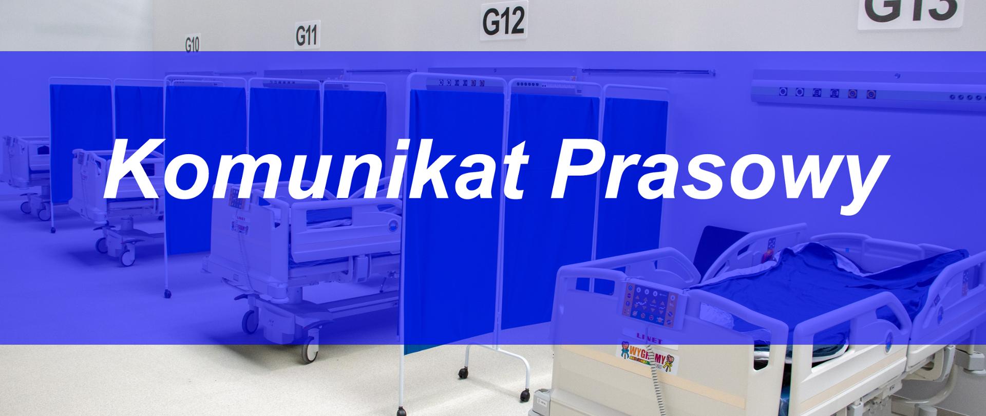 Ilustracja. W tle zdjęcie wnętrza szpitala tymczasowego w Opolu - sali dla chorych. Na pierwszym planie granatowa belka z napisem "Komunikat prasowy". 