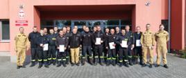 Uczestnicy szkolenia stoją przed budynkiem KP PSP Turek pozując do zdjęcia. 