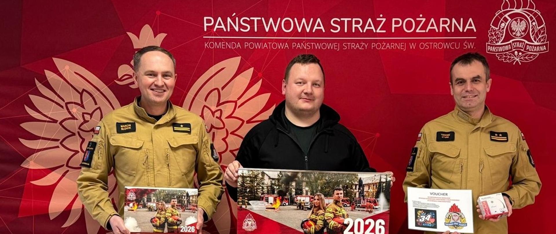 Na zdjęciu widoczny jest Zastępca Komendanta Powiatowego Państwowej Straży Pożarnej w Ostrowcu Św., Naczelnik Wydziału Operacyjno-Szkoleniowego oraz przedsatwiciel organizarora WOŚP na terenie powiatu ostrowieckiego podczas przekarzywania przedmiotów na licytację. Mężczyżni znajdują się na czerwonym tle Państwowa Straż Pożarna.
