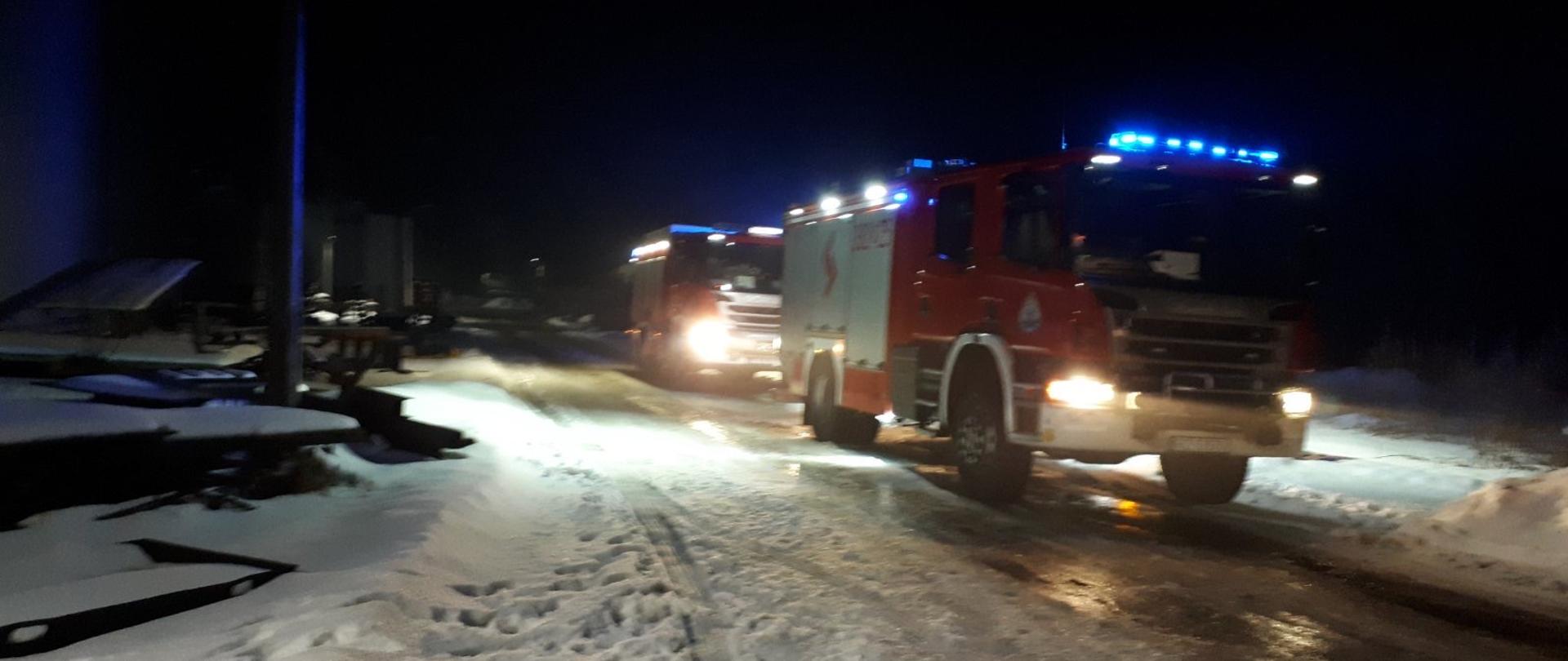 Pora nocna. Na ośnieżonej drodze zakładowej stoją dwa samochody ratowniczo-gaśnicze. 