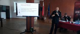 Przemawia zastępca komendanta głównego PSP nadbryg. dr inż Adam Konieczny, po lewej stronie wyświetlana jest prezentacja