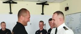 Na zdjęciu widać Komendanta Miejskiego PSP w Kaliszu wręczającego dyplomy na zakończenie kursu. Zdjęcie w ciągu dnia