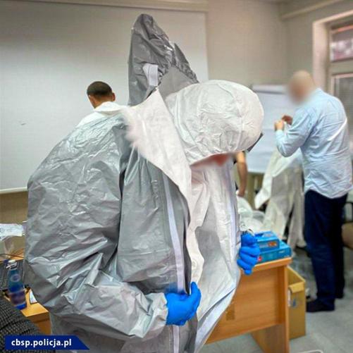 Kilka osób zakłada na siebie kombinezony ochronne.