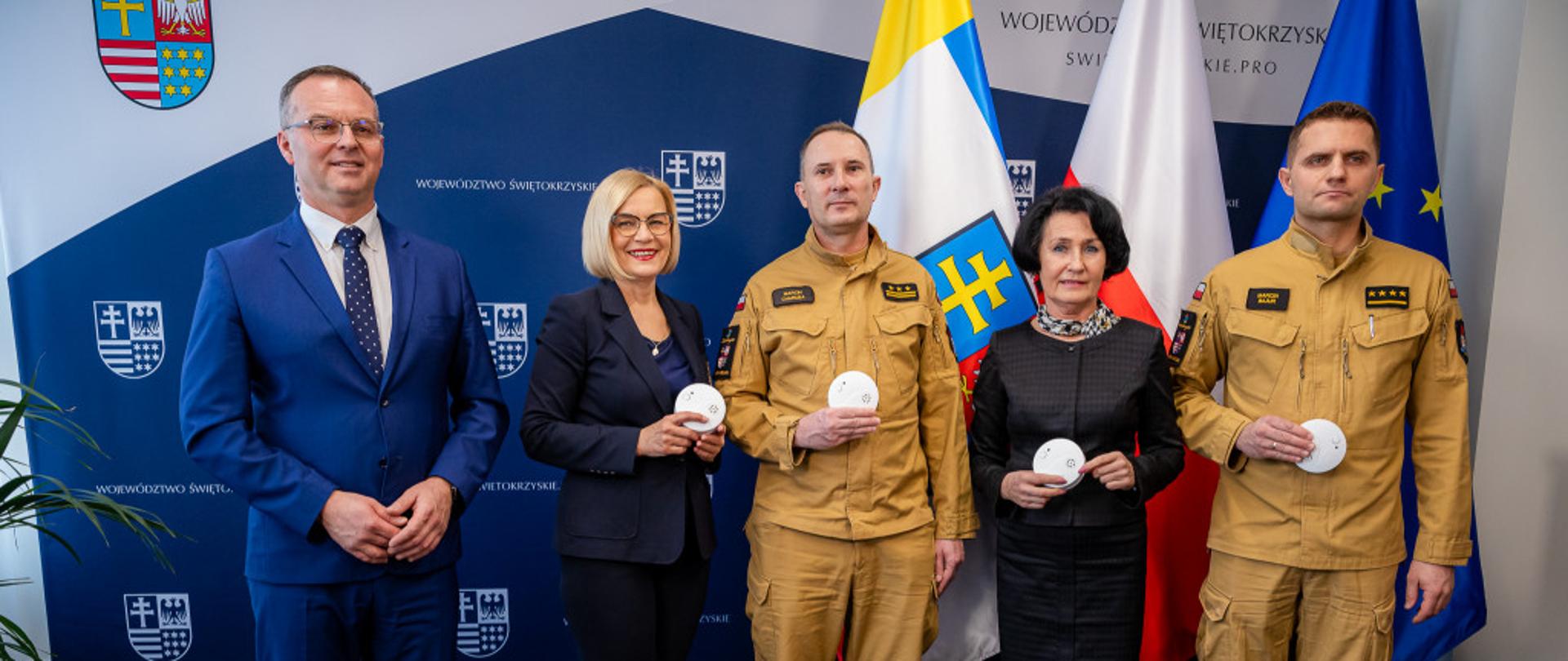 Na zdjęciu strażacy oraz przedstawiciele władz wraz z czujnikami dymu