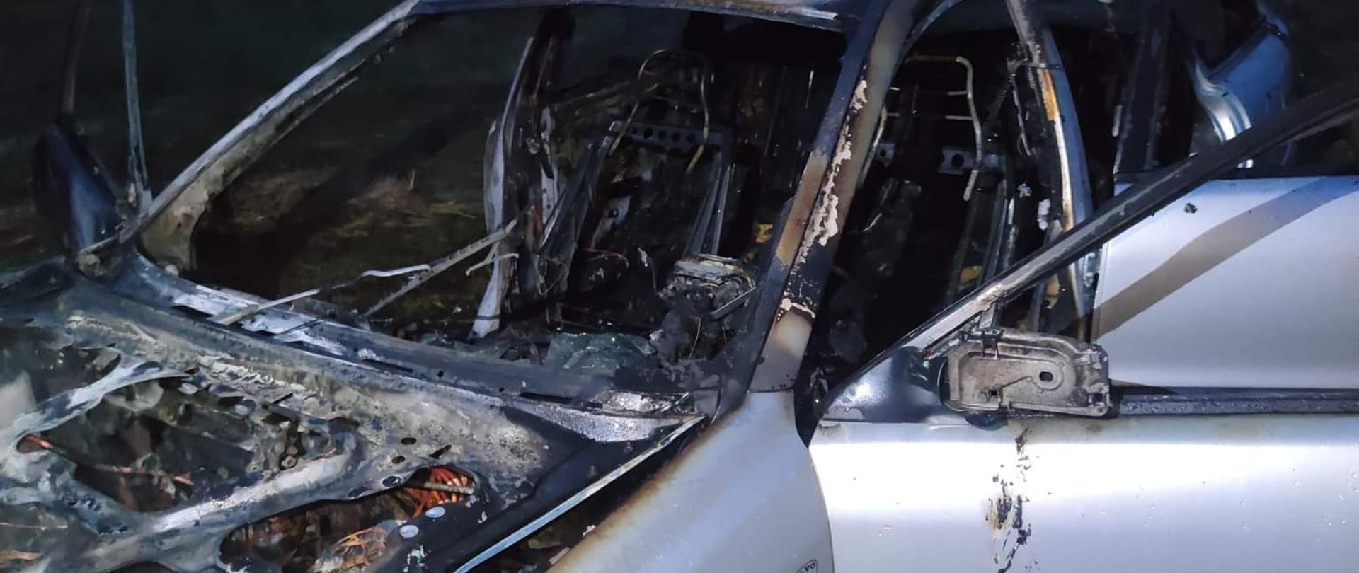Zdjęcie przedstawia zniszczony przez pożar samochód osobowy.
