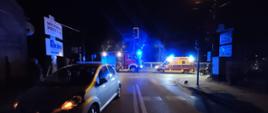 Na zdjęciu motorower oraz samochód osobowy biorący udział w zdarzeniu w oddali zastęp PSP i Zespół Ratownictwa Medycznego.