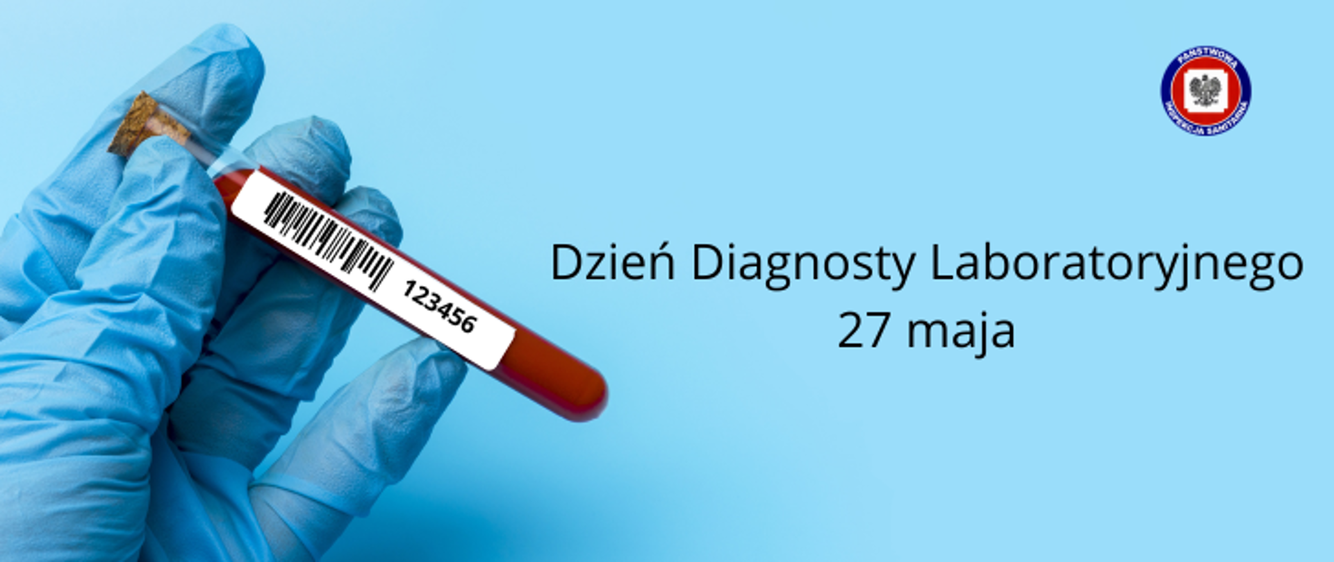 Na niebieskim tle po lewej dłoń w niebieskiej lateksowej rękawiczce trzymająca fiolkę z krwią, po prawej ciemny napis Dzień Diagnosty Laboratoryjnego, poniżej "27 maja". W prawym górnym rogu logo Państwowej Inspekcji Sanitarnej.