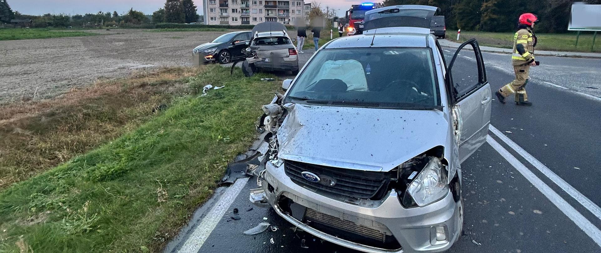 Na zdjęciu widać rozbite pojazdy oraz w tle pojazd straży pożarnej 