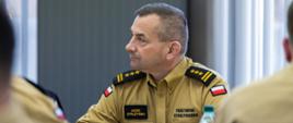 Wielkopolski Komendant Wojewódzki PSP uczestniczy w odprawie, wsłuchuje się w wystąpienie prelegenta.