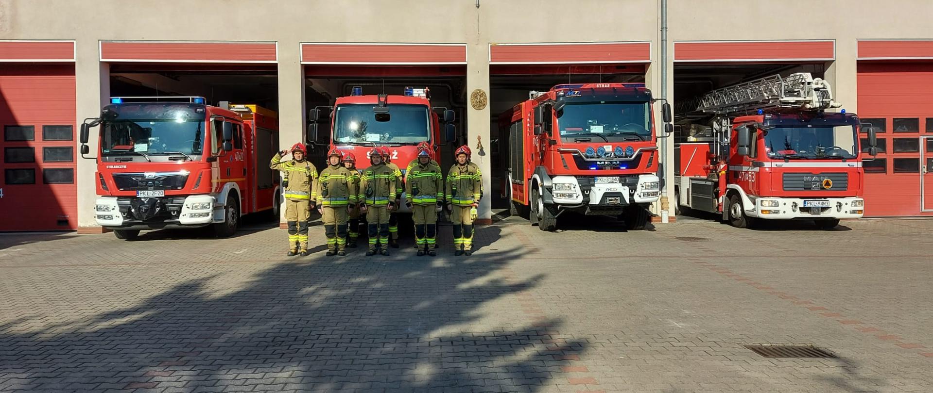 Zdjęcie przedstawia 9 strażaków na tle samochodów pożarniczych oddających hołd poległym strażakom z Ukrainy.