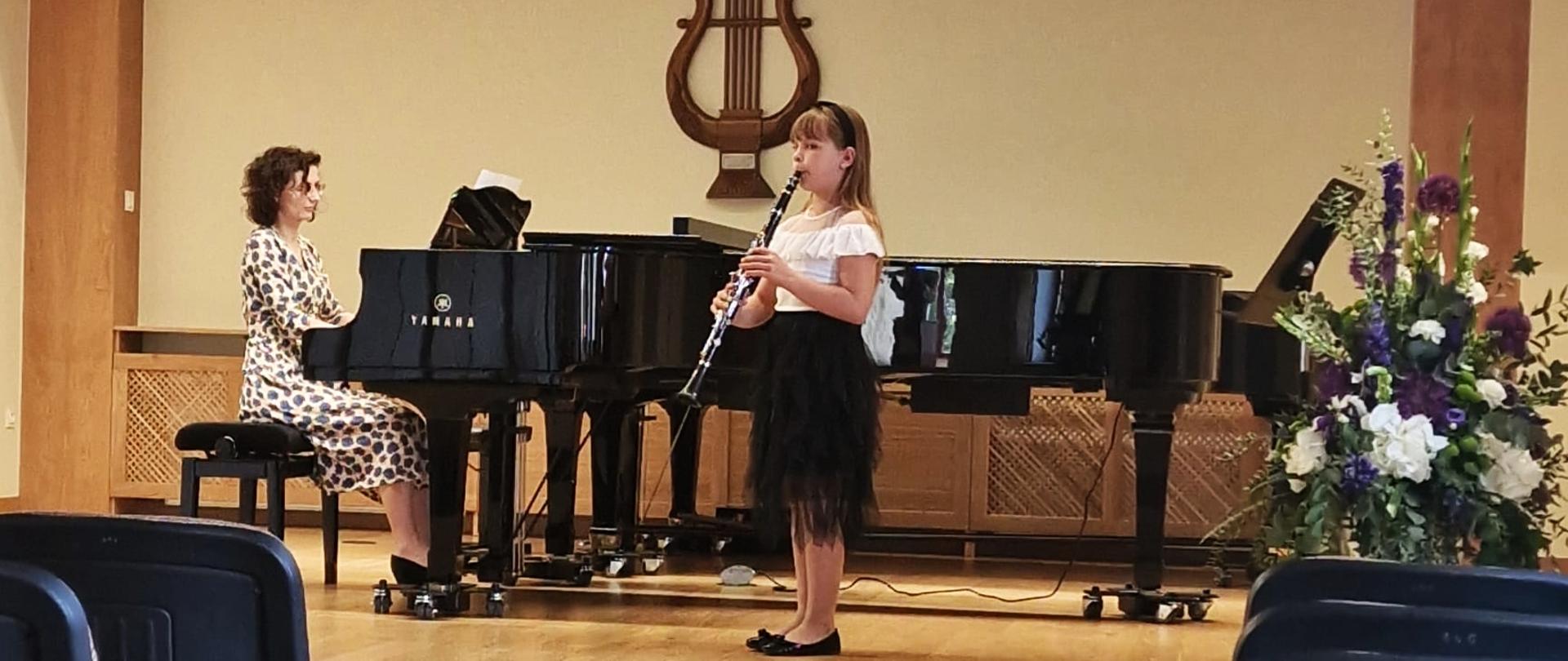na scenie uczennica grająca na klarnecie wraz z akompaniamentem fortepianu