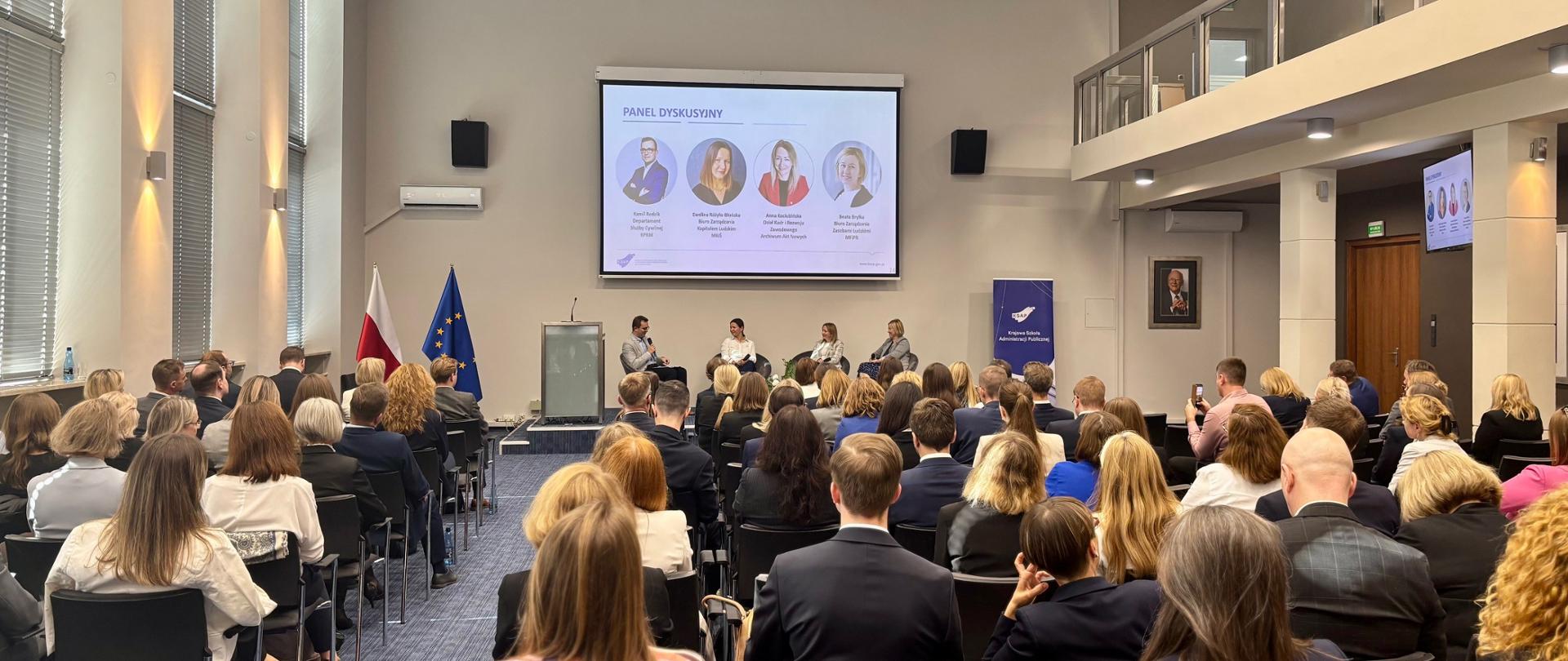 Konferencja absolwentów - Aula pełna ludzi, dyskusję prowadzi czterech panelistów