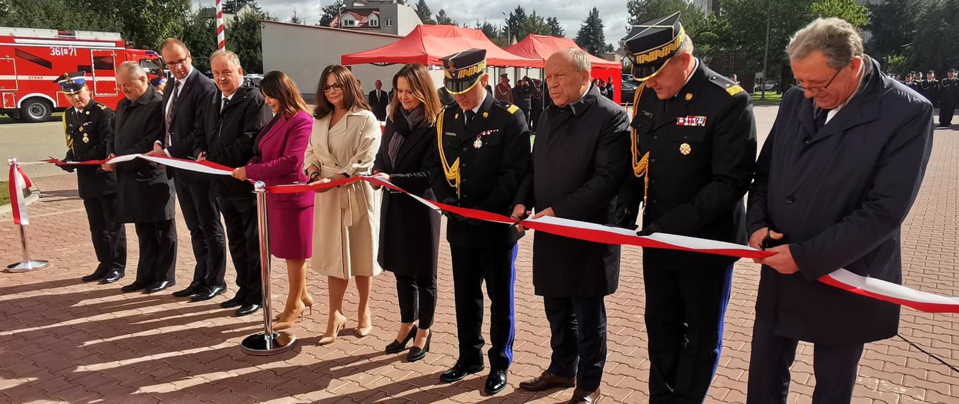 W szeregu ustawiona są osoby które przecinają biało-czerwoną wstęgę.