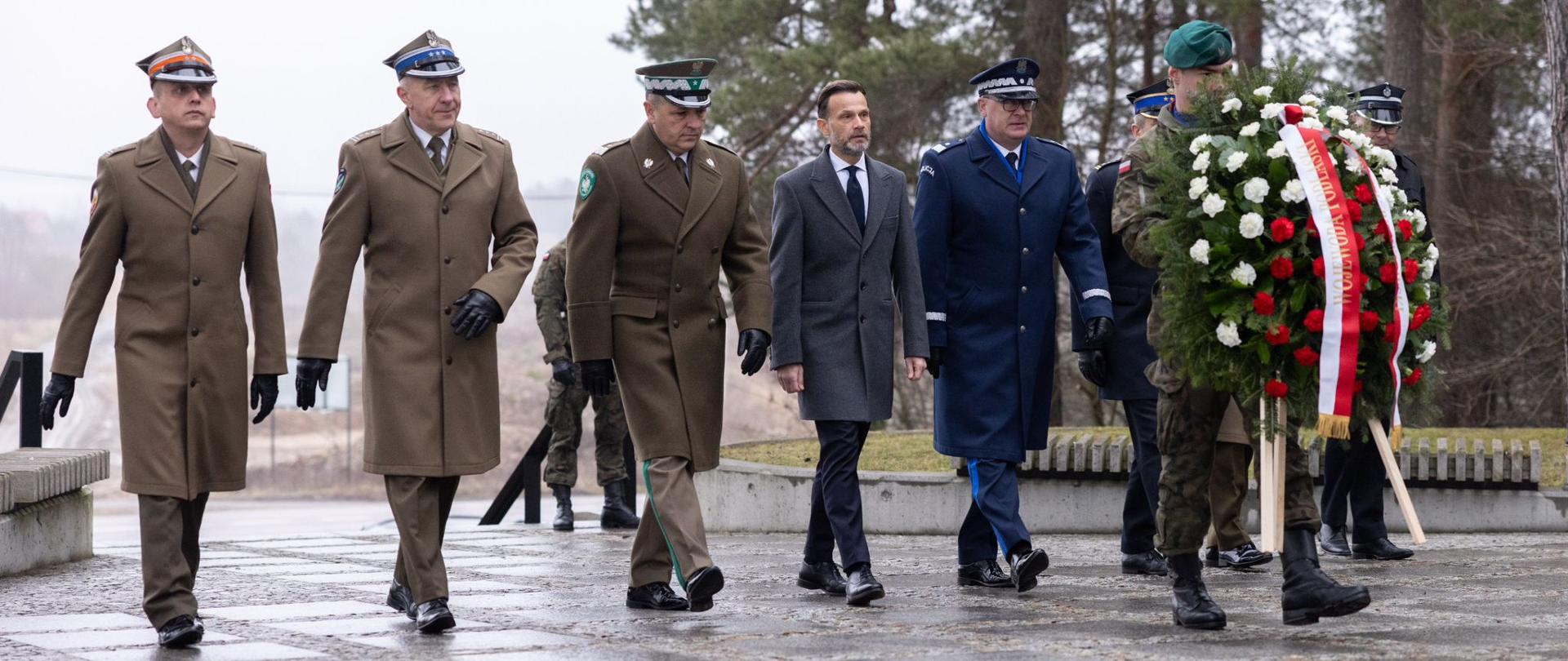 Wojewoda Jacek Brzozowski w asyście służb mundurowych składa wieniec pod monumentem upamiętniającym powstańców styczniowych walczących w Podlaskiem