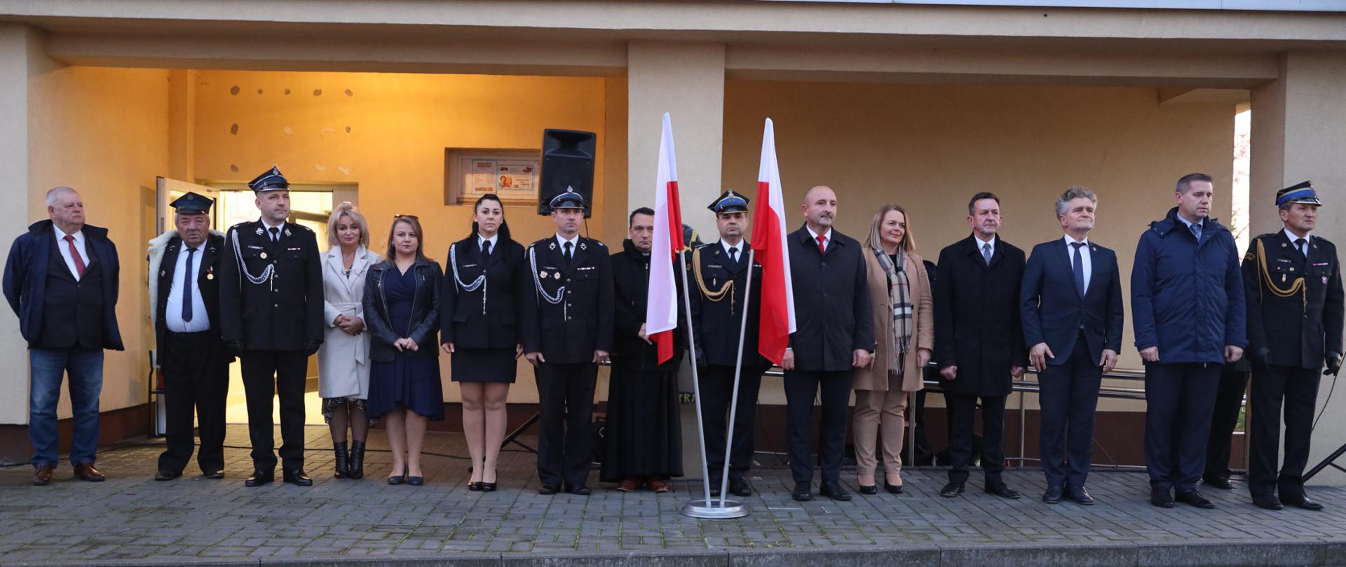 Zdjęcie przedstawia gości i organizatorów zebranych przed wejściem do strażnicy OSP.