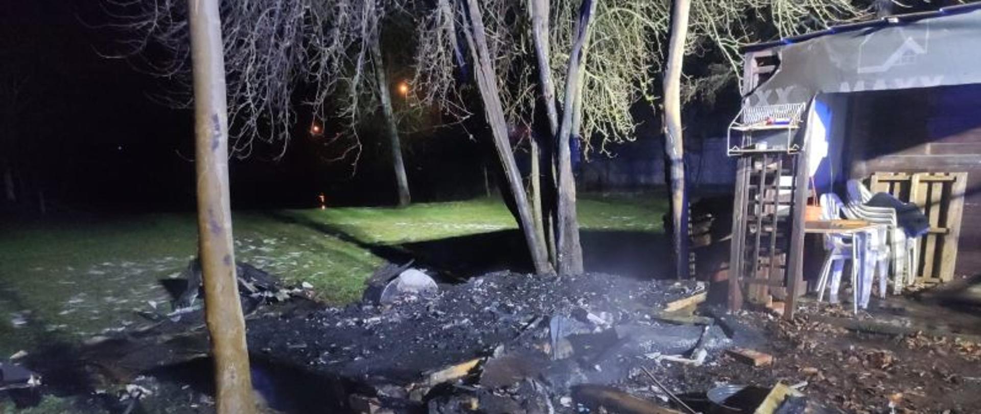 Na zdjęciu widać pogorzelisko po spalonej przyczepie. Centralny punkt stanowi zwęglony wrak. Czarny, okopcony.