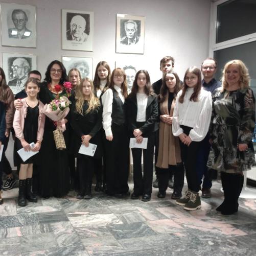 Zdjęcie grupowe uczestników koncertu w Białymstoku z solistką Katarzyną Makal-Żmuda w hallu przed salą koncertową.