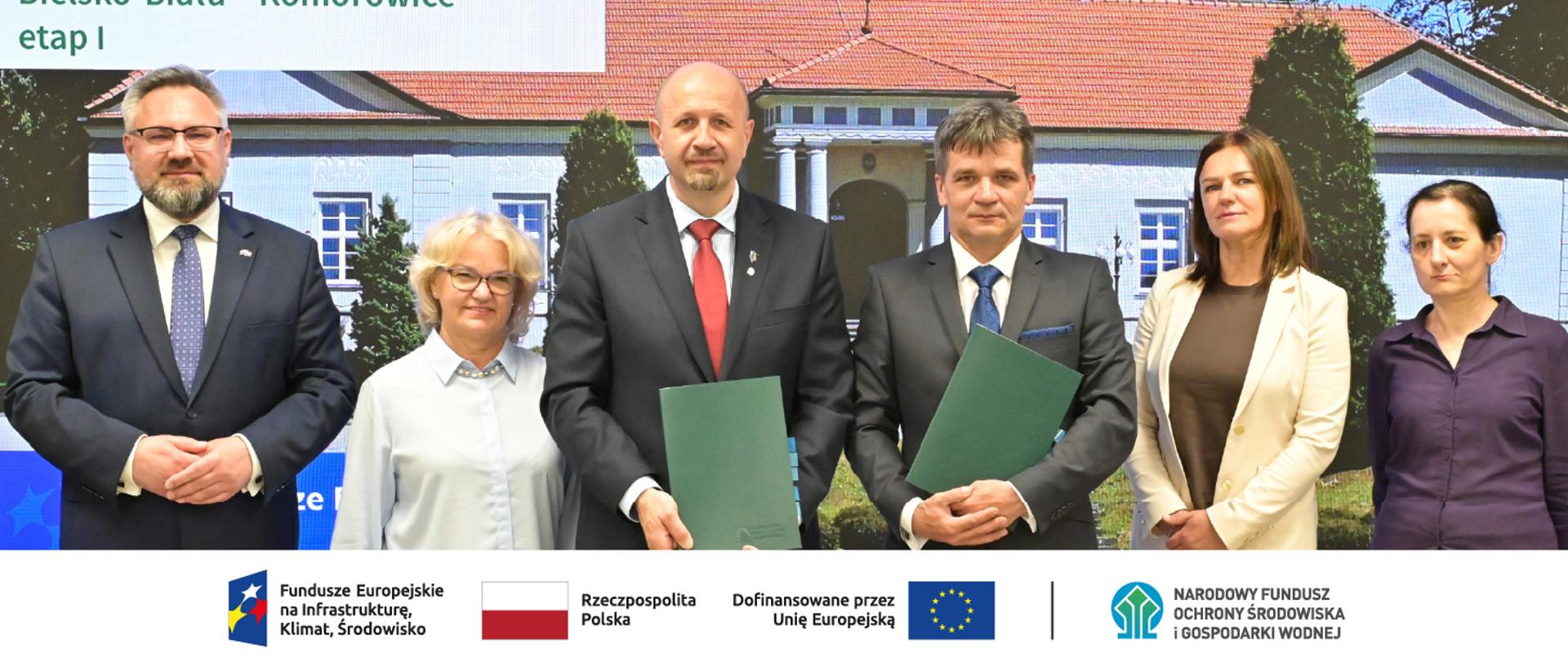 Podpisujący umowę stoją z teczkami w ręku