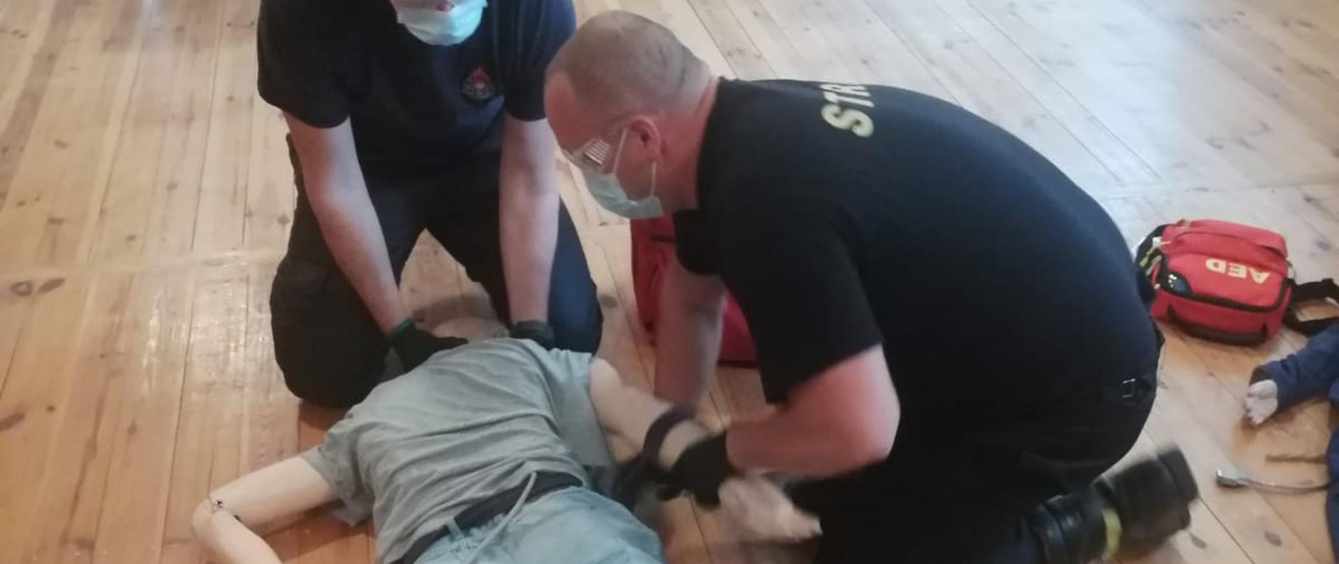 Zdjęcie przedstawia strażaków w trakcie egzaminu z kwalifikowanej pierwszej pomocy