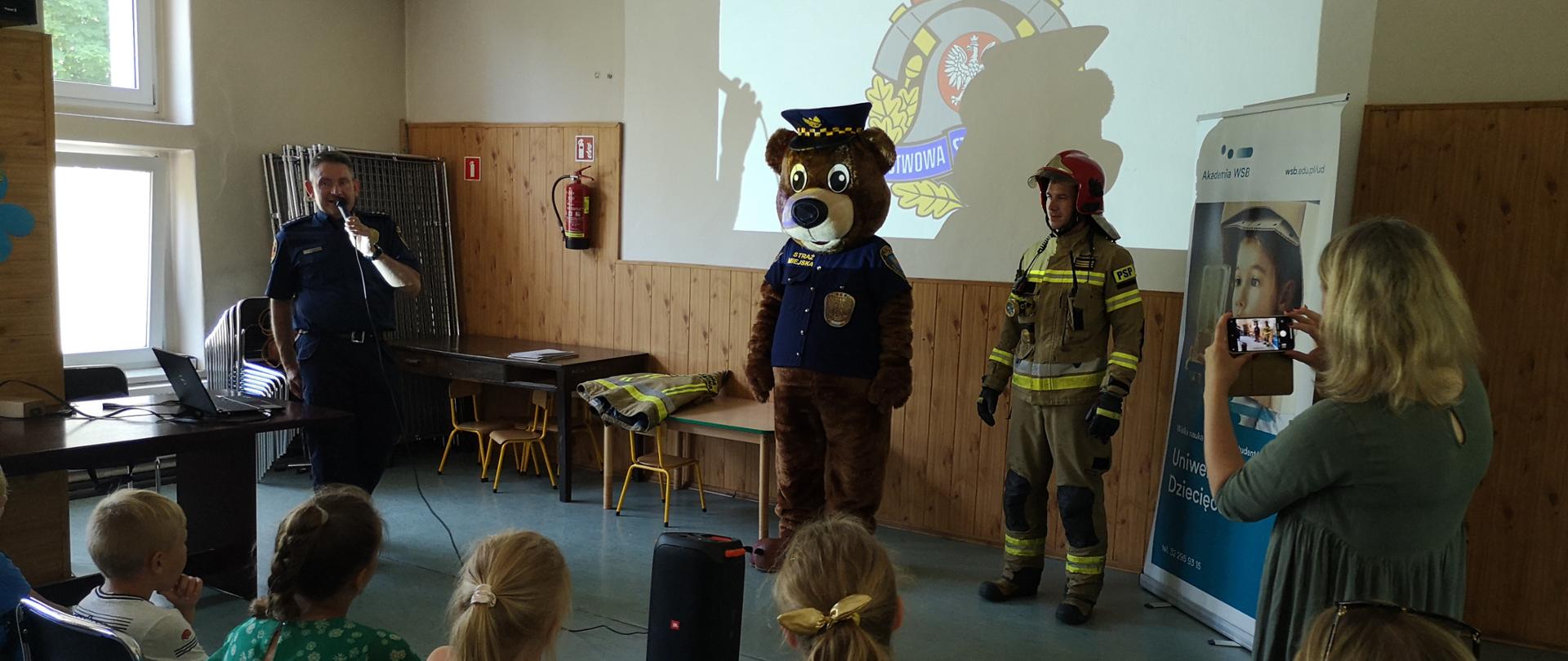 Zdjęcie przedstawia strażaka, strażnika miejskiego oraz maskotkę "Świonka".