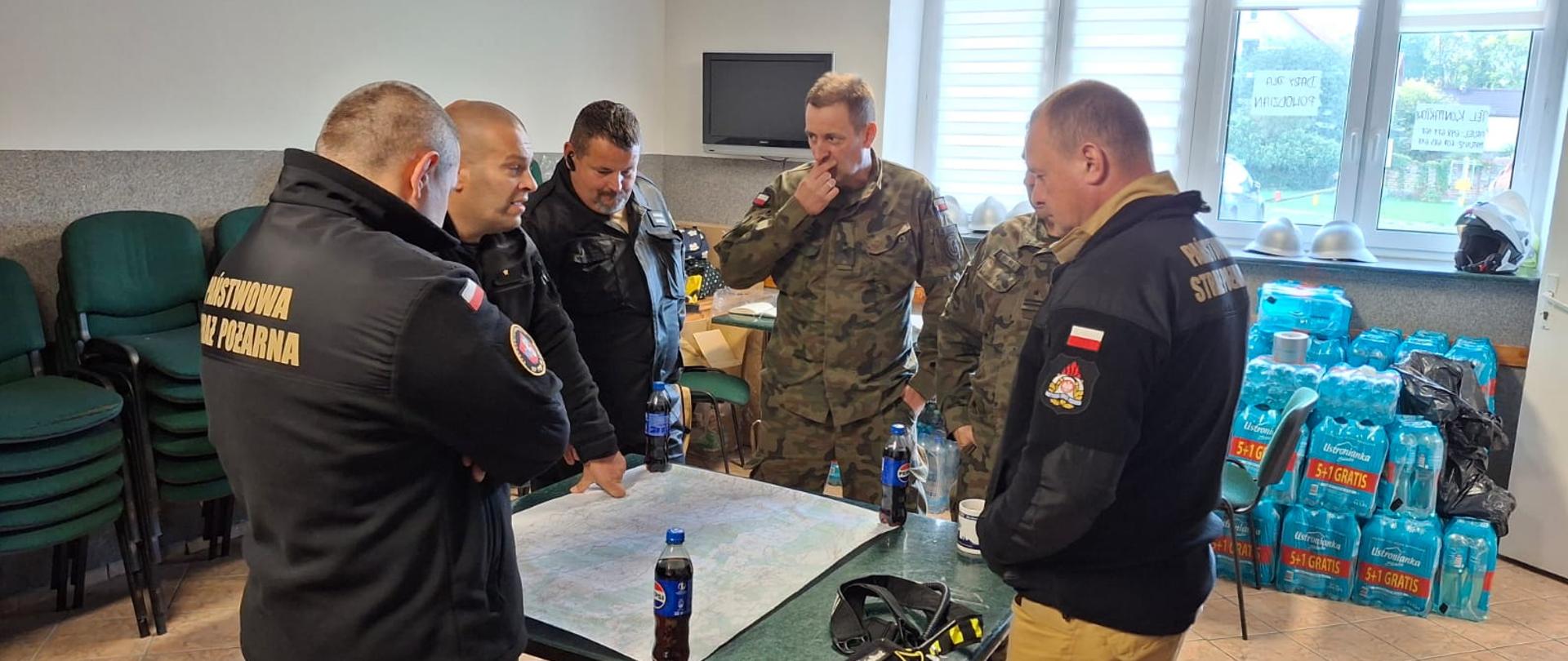 Strażacy i żołnierze podczas omówienia działań przeciwpowodziowych.
