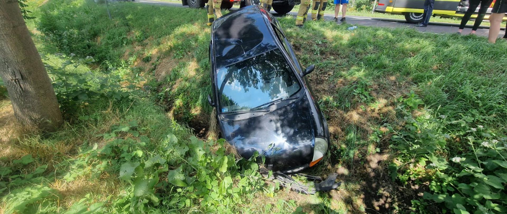 Granatowy samochód znajduje się w rowie, uszkodzony przód