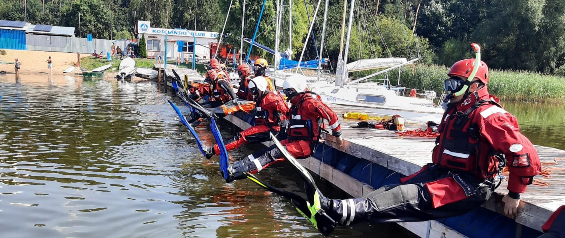 SZKOLENIE Z RATOWNICTWA NA OBSZARACH WODNYCH REALIZOWANEGO PRZEZ KSRG W ZAKRESIE PODSTAWOWYM. Strażacy podczas ćwiczeń nad wodą, wskakują do wody z pomostu
