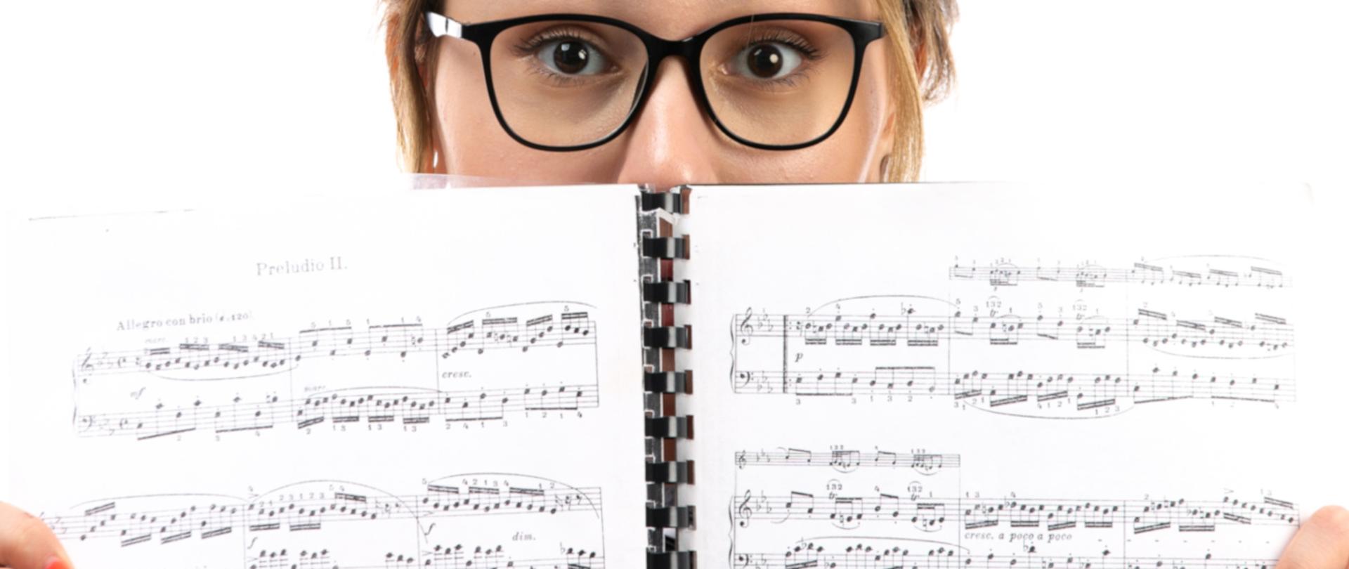 Młoda kobieta w okularach ze otartymi zbindowanymi nutami 