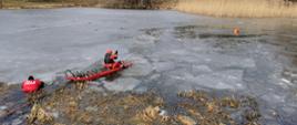 Ratownicy podejmują osoby poszkodowane z pękniętego lodu. Działania z wykorzystaniem deski do ratownictwa lodowego.